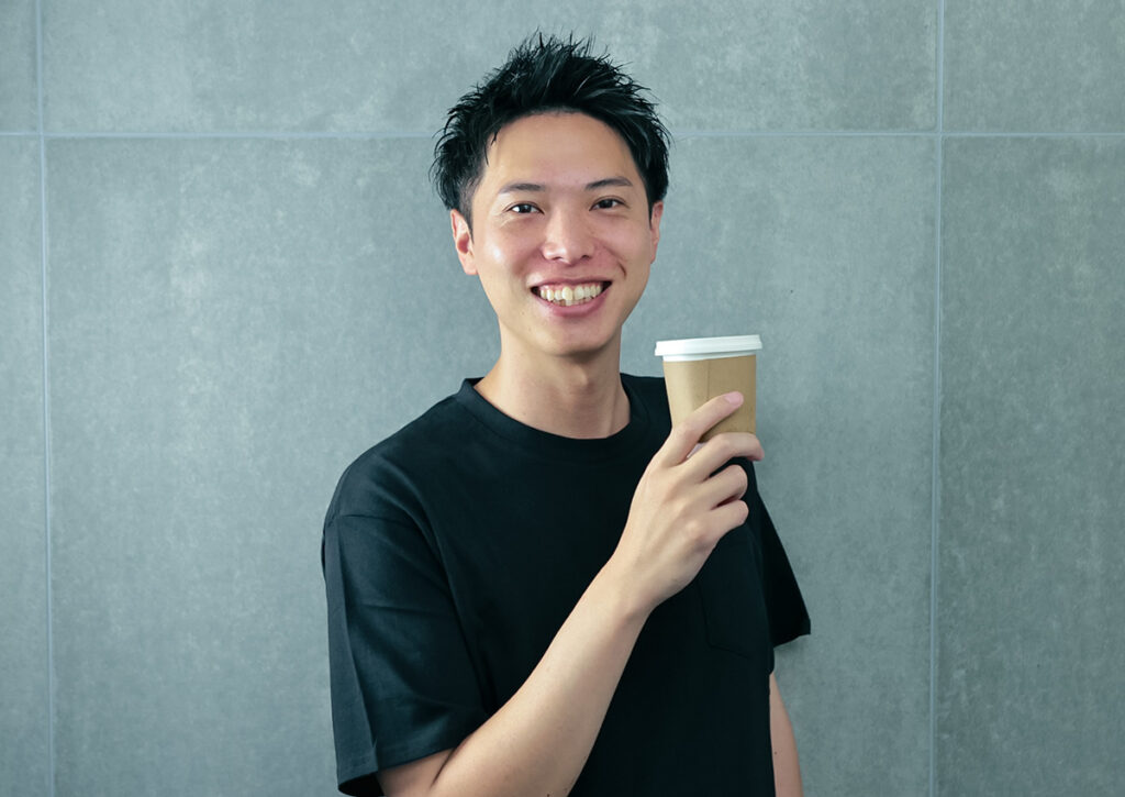 笑顔でコーヒーを持つカメラマン